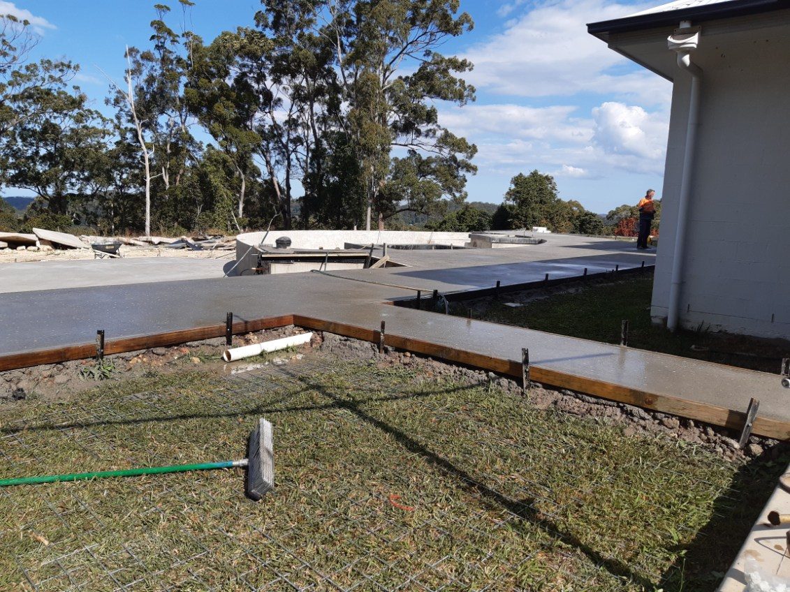 Formwork and steel mesh set out for a large concrete slab beside a house